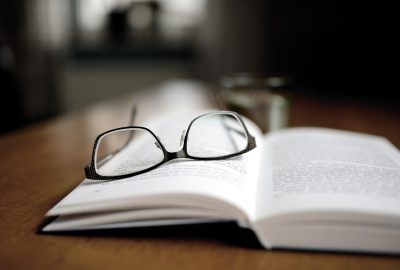 a pair of reading glasses rest atop an open book on a table